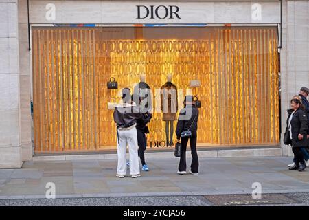 Les gens qui passent devant regardant dans la vitrine Dior sur Bond Street à l'automne octobre 2024 Londres Angleterre Royaume-Uni KATHY DEWITT Banque D'Images