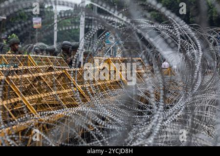 Dhaka, Bangladesh. 23 octobre 2024. Outre les barricades, des clôtures de barbelés ont été installées à l'entrée principale de la maison du Président (Bangabhaban) pendant la manifestation. Des membres des forces de l'ordre en alerte devant Bangabhaban. L'entrée principale de la maison du président (Bangabhaban) alors que les manifestants organisent une manifestation devant elle, exigeant la démission du président Mohammed Shahabuddin après son commentaire sur la démission de l'ancien premier ministre Sheikh Hasina, à Dhaka, au Bangladesh. Crédit : SOPA images Limited/Alamy Live News Banque D'Images