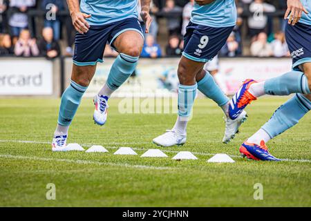 Joueurs de football jambes et pieds dans la tenue de football bleu clair et foncé, échauffement avant un match en cours entre des cônes blancs. Crédit John Rose/Alamy Banque D'Images