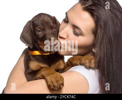 Brune fille embrassant son chiot isolé sur fond blanc Banque D'Images