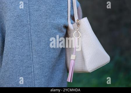 Femme avec porte-clés en cuir rose sur son sac à l'extérieur, gros plan Banque D'Images