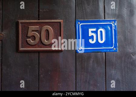 Cinquante-cinquante : double 50 affichage sur panneau brun et plaque bleue, forme carrée sur une porte d'entrée en bois Banque D'Images