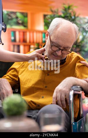 Infirmière saut pour aider l'homme âgé en fauteuil roulant perdre conscience lors d'une visite à domicile, personne âgée hyperventilant et effrayant sa femme. Assistant médical en panique vérifiant le pouls. Gros plan. Banque D'Images