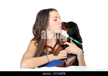 Fille embrassant son chiot doberman Banque D'Images