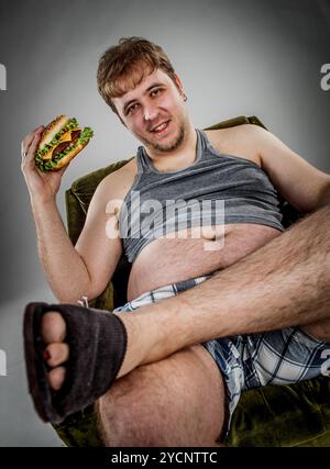 Gros homme mangeant un hamburger Banque D'Images