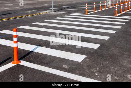 Lignes de circulation blanc avec un passage pour piétons sur un parking d'asphalte gris Banque D'Images