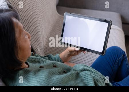 femme senior asiatique se relaxant sur le canapé à l'aide de la tablette à la maison, profitant du temps calme, de l'espace de copie, à la maison Banque D'Images