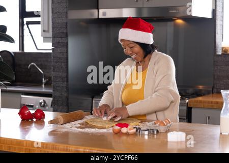 Femme senior asiatique faisant des biscuits de noël à la maison, souriant joyeusement Banque D'Images