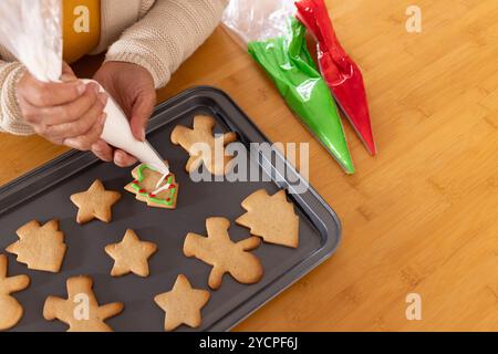 Femme senior asiatique décorant des biscuits de noël avec de la cerise sur une plaque de cuisson, à la maison Banque D'Images