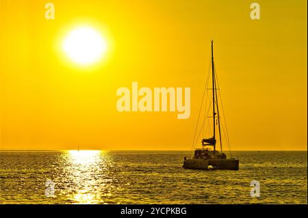 Catamaran voilier sur coucher de soleil doré Banque D'Images