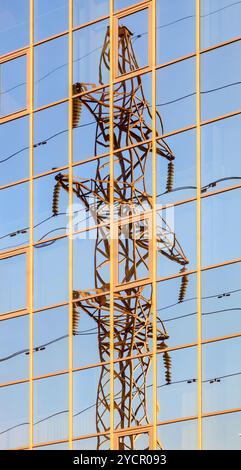 Tour électrique haute tension se reflète dans les fenêtres de l'immeuble en miroir Banque D'Images