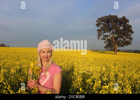 Femme debout dans un champ de ferme de canola doré Banque D'Images