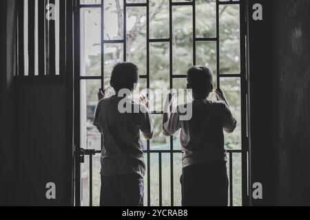 Le dos de deux enfants enfermés dans une cage de fer. Victime enfant enfermé dans une cellule de cage, dans le stress émotionnel et la douleur, enfants violence et maltraités. Banque D'Images