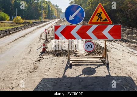 Chantier de construction sur une route de campagne avec un ensemble de panneaux de signalisation routière dirigeant les véhicules. Détour routier temporaire et zone limite de vitesse en raison de la construction en cours Banque D'Images