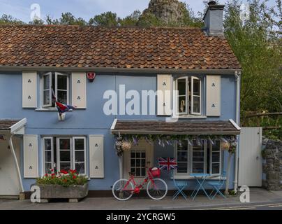 Cheddar, Royaume-Uni, 1er septembre 2022 : Maison pittoresque dans le centre du village avec un bicylce rouge et le drapeau de l'Union Jack, Europe Banque D'Images