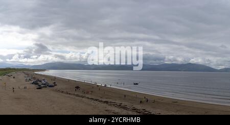 Inch Strnad, Irlande, 5 août 2022 : paysage panoramique d'Inch Strand dans la baie de Dingle avec de nombreuses voitures et amateurs de plage sur une journée nuageuse d'été, en Europe Banque D'Images