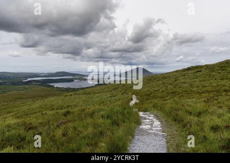 Le sentier de randonnée descendant du sommet de la montagne Diamond Hill dans le parc national du Connemara avec vue sur la côte et Kingstown Peninusla Banque D'Images