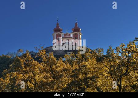 Banska Stiavnica, Slovaquie, 28 septembre 2022 : vue du calvaire rouge Banska Stiavnica sous un ciel bleu avec forêt d'automne au premier plan, Europe Banque D'Images