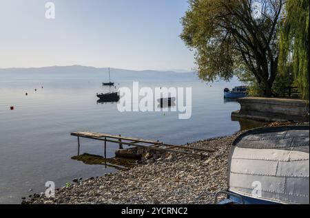 Plusieurs bateaux en bois ancrés dans les eaux calmes du lac Ohrid près de Kaneo par une belle journée d'automne Banque D'Images