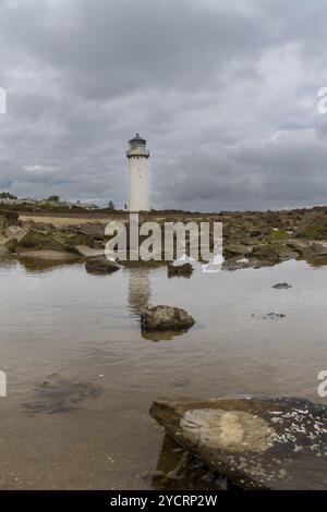 Vue sur le phare historique de la Southerness en Écosse avec réflexions dans les bassins de marée en premier plan Banque D'Images