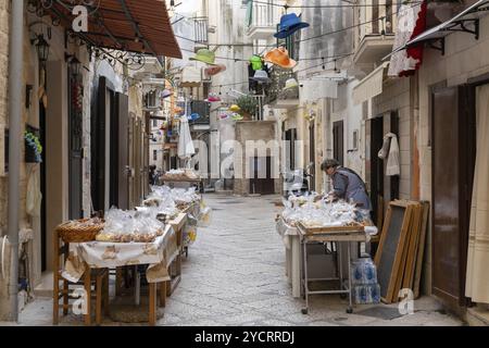 Bari, Italie, 27 novembre 2023 : L'emblématique Strada Arco Basso dans la vieille ville historique de Bari Vecchio avec une femme présentant des pâtes fraîches à vendre Banque D'Images