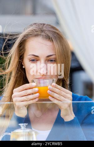 Femme avec tasse de thé. Thé avec argousier et miel sur fond de café. Banque D'Images