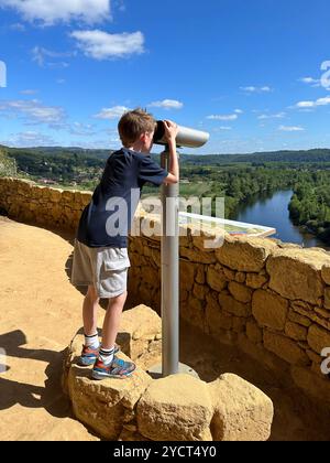 Jeune garçon regardant à travers un télescope touristique le long de la rivière Dordogne Banque D'Images