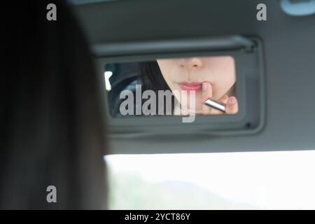 La bouche de la femme fixant son maquillage dans le miroir Banque D'Images