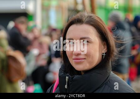 Portrait de rue d'une belle femme de 30-35 ans sur un fond de ville flou. Banque D'Images