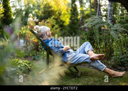 Femme mature se relaxant dans un transat dans son jardin Banque D'Images