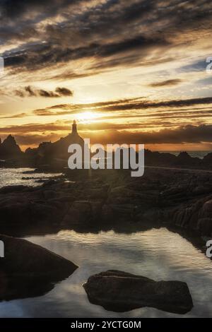 Phare du Corbière au coucher du soleil à marée basse. Réflexion au premier plan. Banque D'Images