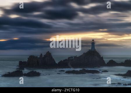 Phare du Corbière se dresse sur une île rocheuse entourée d'eau au crépuscule. Banque D'Images