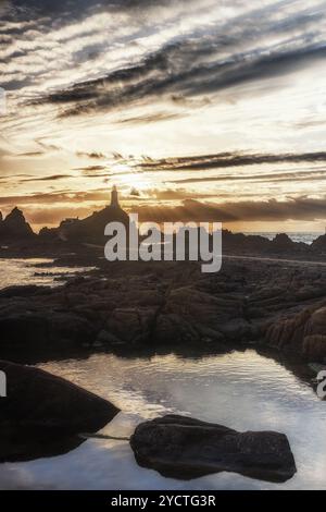 Phare du Corbière au coucher du soleil à marée basse. Réflexion au premier plan. Banque D'Images