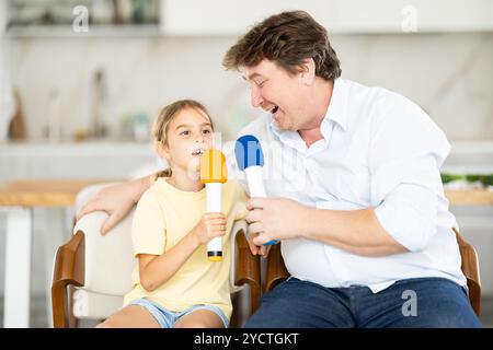 Père et fille chantant karaoké avec des micros Banque D'Images