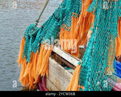 Filets de pêche colorés vert et orange suspendus pour sécher sur la poupe d'un bateau de pêche à Whitby Harbour, dans le North Yorkshire. Banque D'Images