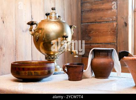 Ancien samovar en cuivre traditionnel pour le thé et articles en céramique sur une table dans une maison rurale Banque D'Images