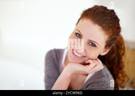 Portrait, fille et se détendre avec le sourire à la maison pour le calme matin, week-end pause et la paix avec bien-être. Heureux, femme et se reposer dans un appartement confortable avec Banque D'Images