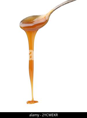 Sauce caramel savoureuse dégouttant de la cuillère sur fond blanc, gros plan Banque D'Images