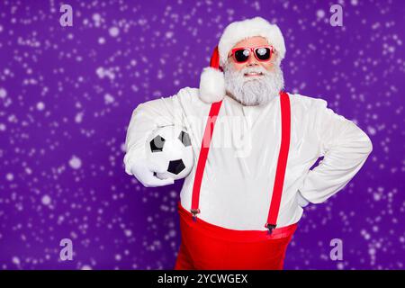 Photo de grey haired santa père holding football ball va dépenser newyear nuit à regarder l'usure caractéristiques techniques ligue de champion sun costume violet isolés Banque D'Images