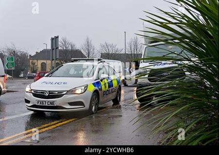Voiture de police avec des lumières clignotantes sous la pluie à côté d'un van arrêté sur le chemin de John Adam. Banque D'Images