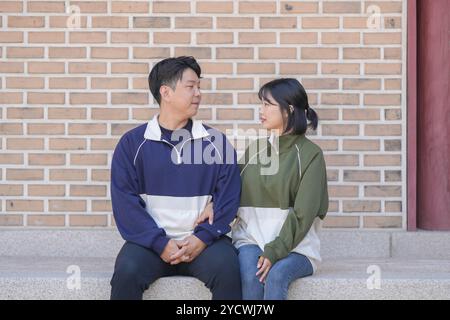 Un couple coréen sportif, un homme dans les années 30 et une femme dans les années 20, portant des survêtements, passe leur temps ensemble heureux dans un bâtiment historique en se Banque D'Images