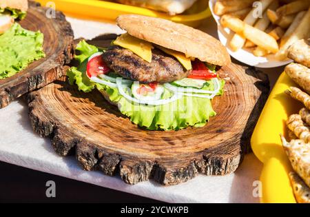 Hamburger avec viande de bœuf, fromage et légumes frais sur planche de bois Banque D'Images