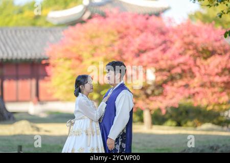 Un couple coréen dans les années 30 et une femme dans les années 20 portent heureusement Hanbok et passent du temps devant de belles feuilles d'automne dans un historique Banque D'Images