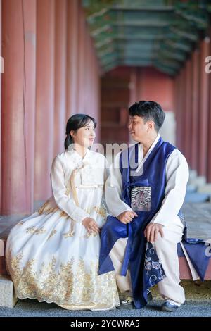 Un couple coréen, un homme de 30 ans et une femme de 20 ans, portent joyeusement Hanbok et sont assis dans un bâtiment historique à Séoul, en Corée du Sud. Banque D'Images