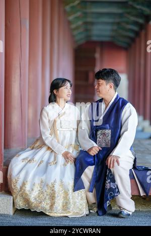 Un couple coréen, un homme de 30 ans et une femme de 20 ans, portent joyeusement Hanbok et sont assis dans un bâtiment historique à Séoul, en Corée du Sud. Banque D'Images