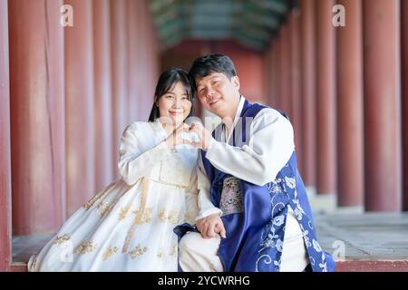 Un couple coréen, un homme de 30 ans et une femme de 20 ans, portent joyeusement Hanbok et sont assis dans un bâtiment historique à Séoul, en Corée du Sud. Banque D'Images