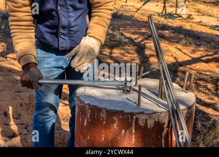 ouvrier africain pliant les barres d'armature manuellement sur la cour de sa maison dans le village Banque D'Images