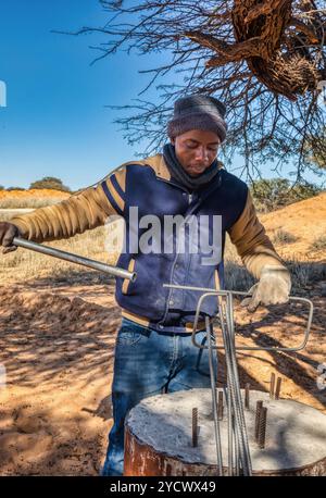 ouvrier africain pliant les barres d'armature manuellement sur la cour de sa maison dans le village Banque D'Images