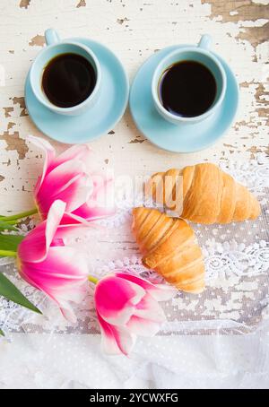 Belle tasse de café, croissants et tulipes roses sur la vieille table blanche Banque D'Images