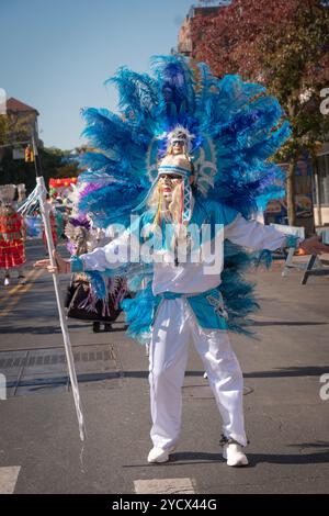 Danseuse du groupe Centro Cultural Bolivia en costume avec masque et plumes bleues au Bolivian Day Parade à Jackson Heights, Queens, New York. Banque D'Images